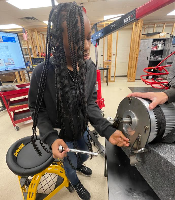 Female student working with a socket wrench to tighten parts